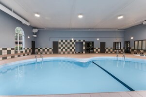 Una piscina con un diseño de pared a cuadros, suelo de baldosas e iluminación empotrada en el techo.
