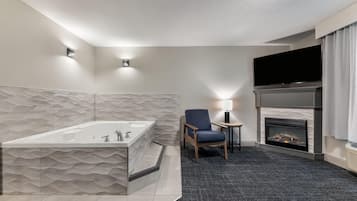A modern bathroom with a freestanding bathtub, a seating area with a chair and a table, and a fireplace.