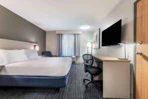 Une chambre d’hôtel équipée d’un lit, d’un bureau, d’une chaise et d’un téléviseur à écran plat.