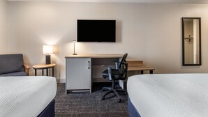 A hotel room with two beds, a desk, a chair, a TV, a lamp, and a mirror. - Days Inn & Suites by Wyndham Thunder Bay (Thunder Bay)