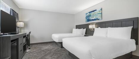 A hotel room with a large bed, a desk with a computer, and a TV.