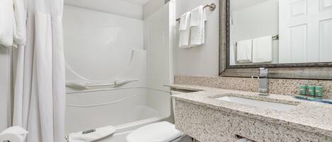 A bathroom with a shower, toilet, sink, and mirror.