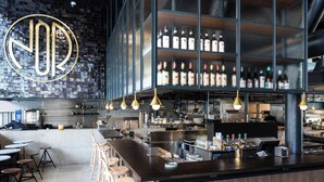 A modern bar with a large illuminated sign, bar stools, and a variety of bottles on shelves. - Clarion Hotel Stockholm (Stockholm)