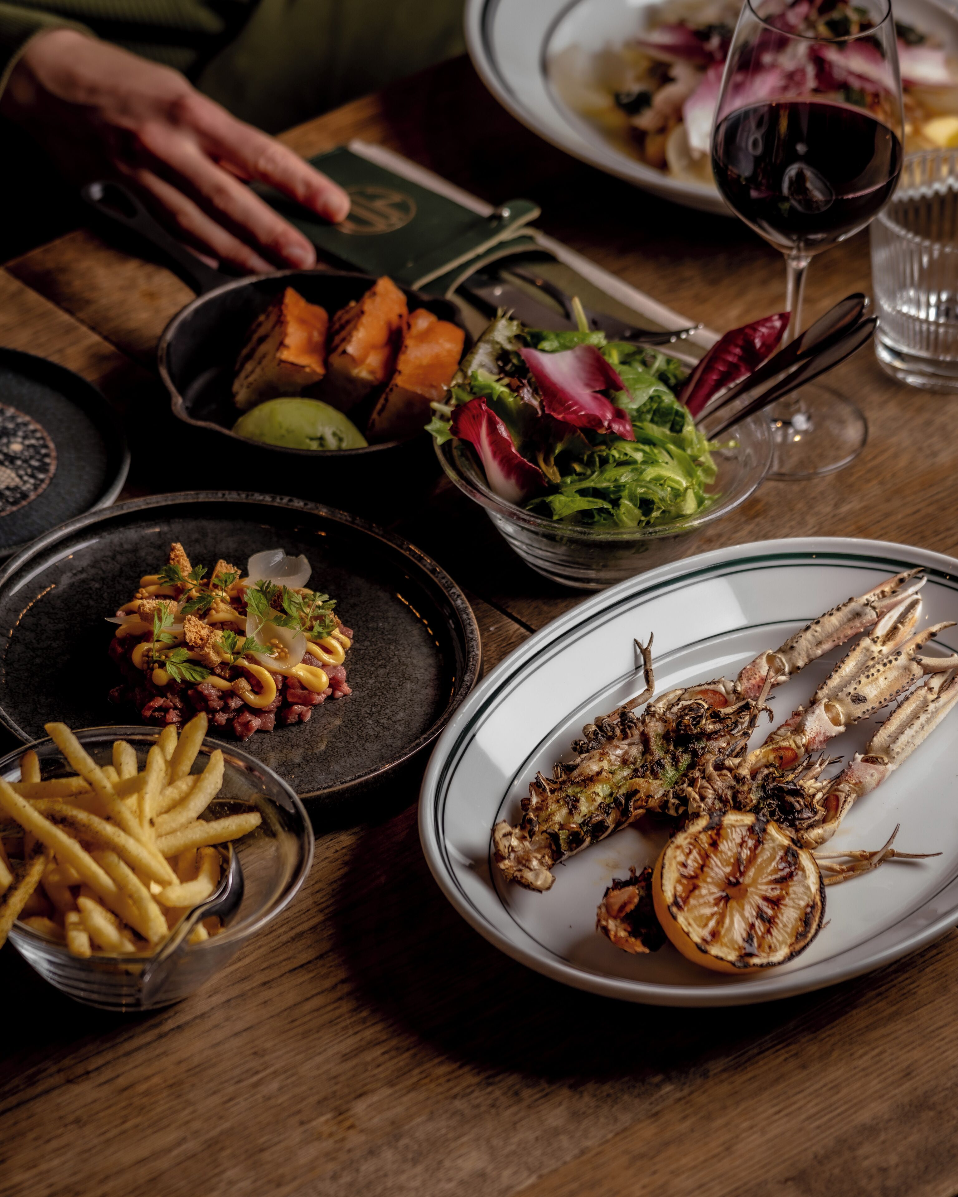 A dining table with various dishes including grilled fish, fries, and a salad.