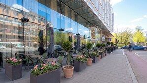 Outdoor seating with potted plants, a glass facade, and a clear sky. - Clarion Hotel Stockholm (Stockholm)