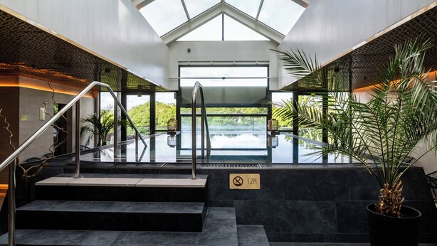 A modern indoor pool area with a glass ceiling, a staircase, and a sign indicating a 1.2M height limit. - Clarion Hotel Stockholm (Stockholm)