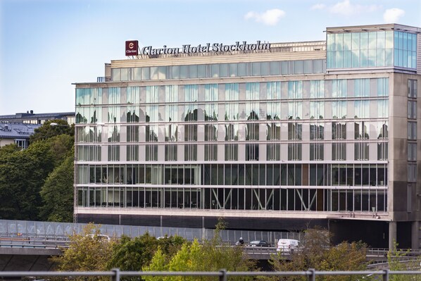 En modern hotellbyggnad med en stor glasfasad och en skylt med texten ”Clarion Hotel Stockholm”.