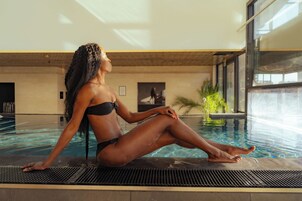 A person sitting by a pool with a view of the outdoors.
