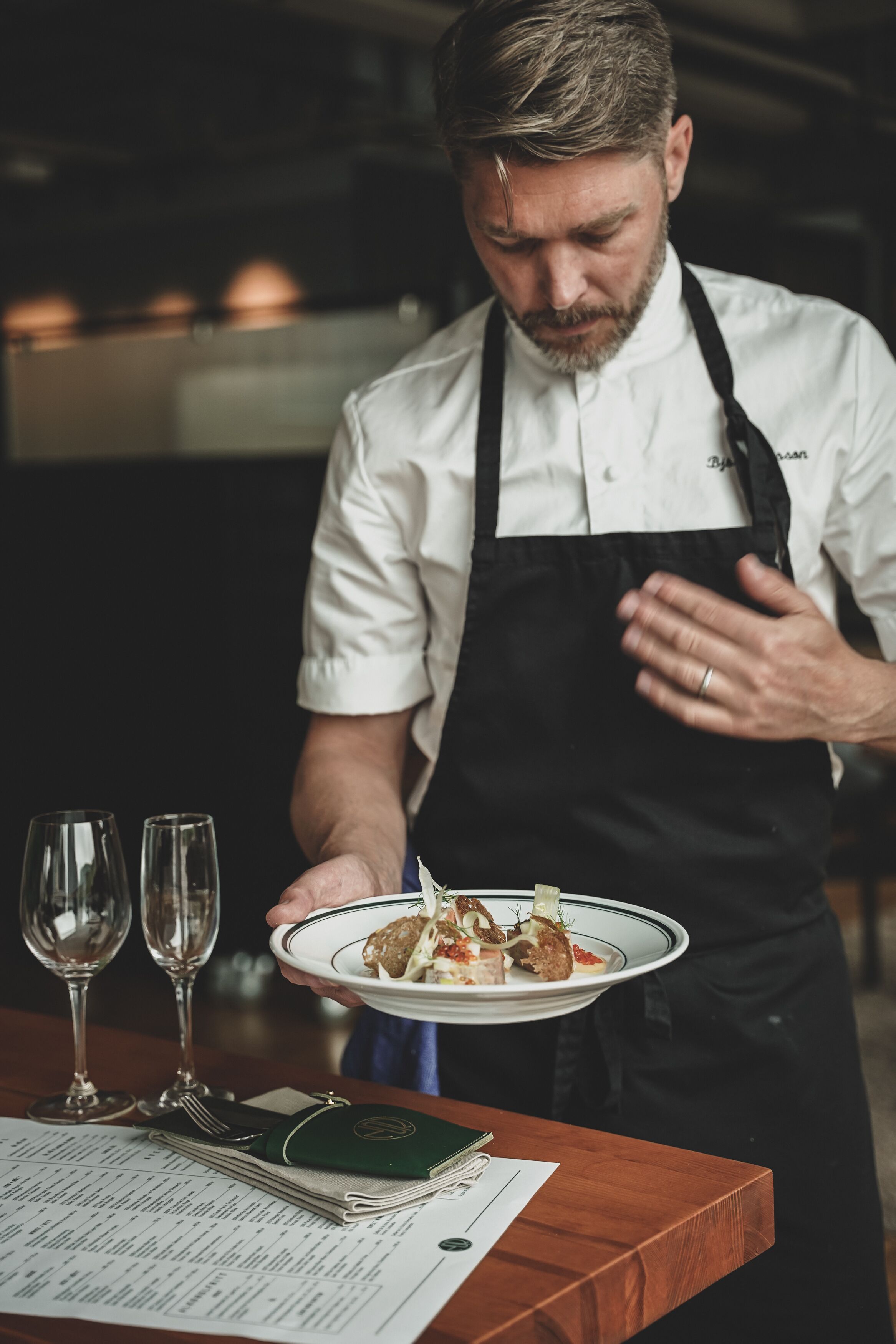 A person in a chef's uniform holding a plate of food.