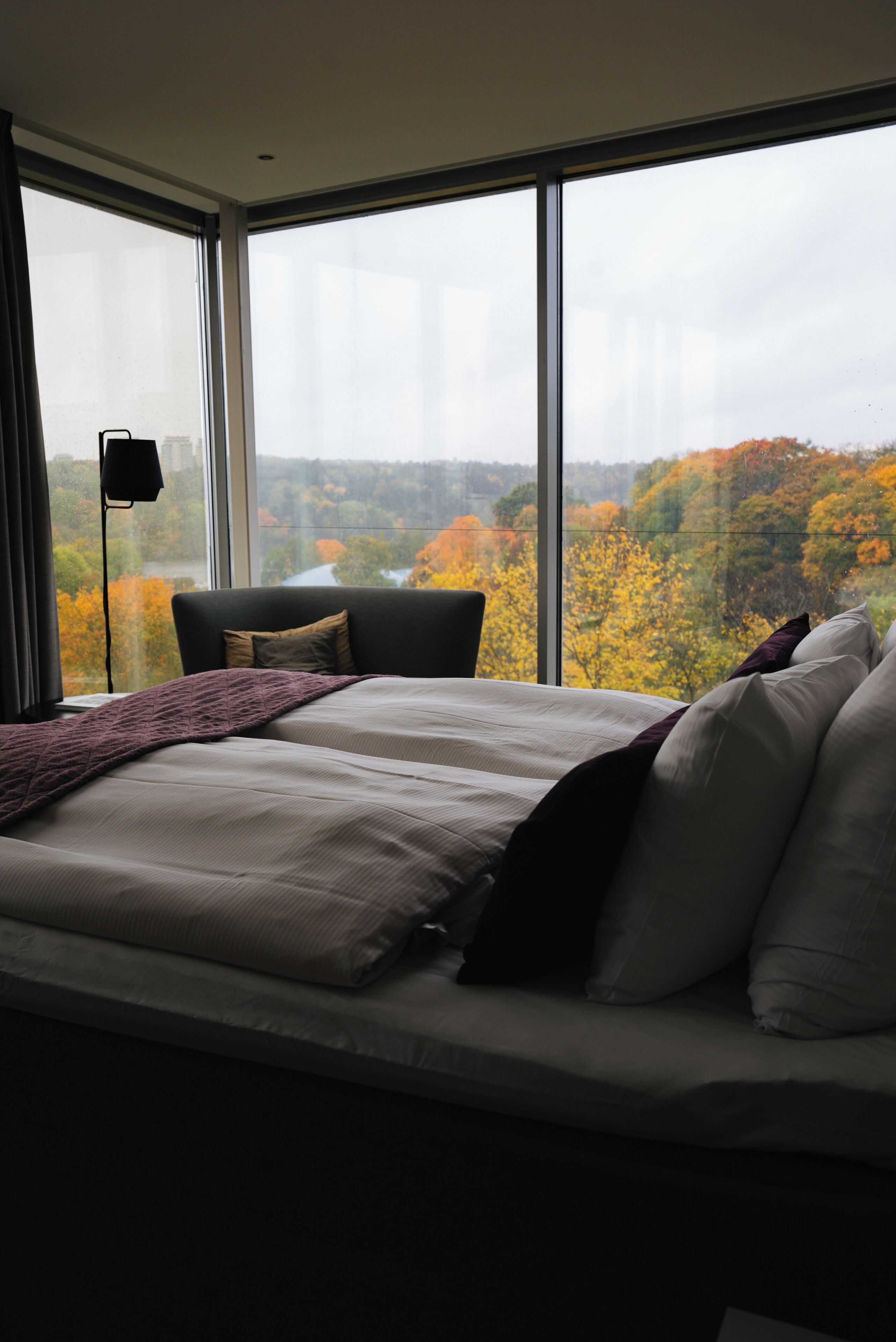 Ein Schlafzimmer mit einem großen Fenster, einem Bett und einem Sessel.