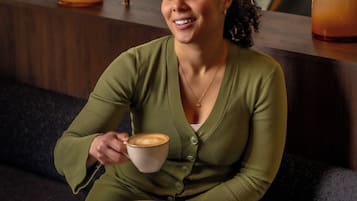 A person sitting at a round table with a cup of coffee and a dessert plate.