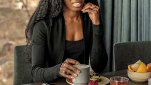 A person seated at a table with a cup, a plate with food, and a bowl of fruit. - Clarion Hotel Stockholm (Stockholm)