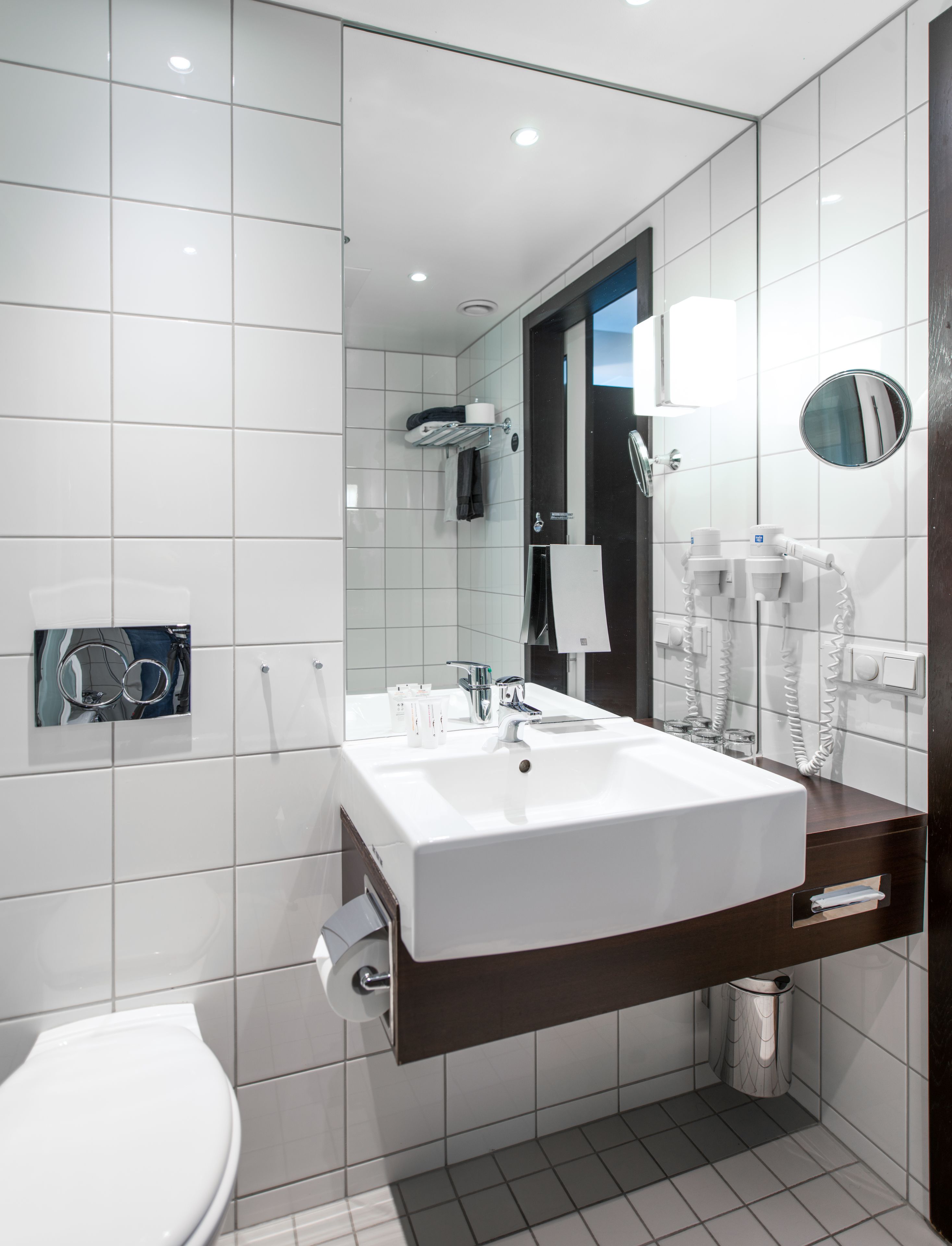 A modern bathroom with a white sink, mirror, and toilet.