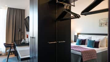 A modern hotel room with a bed, a desk, and a wardrobe.