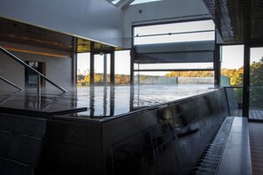 Ett modernt inomhuspoolområde med en glasvägg som ger utsikt över höstlövet.