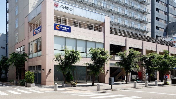 Un hôtel à plusieurs étages au design moderne, avec une enseigne « Comfort Hotel » bien visible, une entrée facilement identifiable et un ciel dégagé au-dessus.