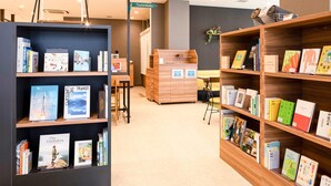 Une bibliothèque avec des étagères, un bureau en bois et un panneau indicateur.