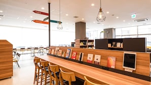 Une bibliothèque ou un espace de lecture moderne, doté de tables et de chaises en bois, d’étagères et de panneaux de signalisation.