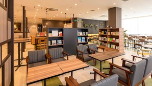 Une bibliothèque moderne dotée de plusieurs espaces de lecture, d’étagères et d’un comptoir d’accueil.