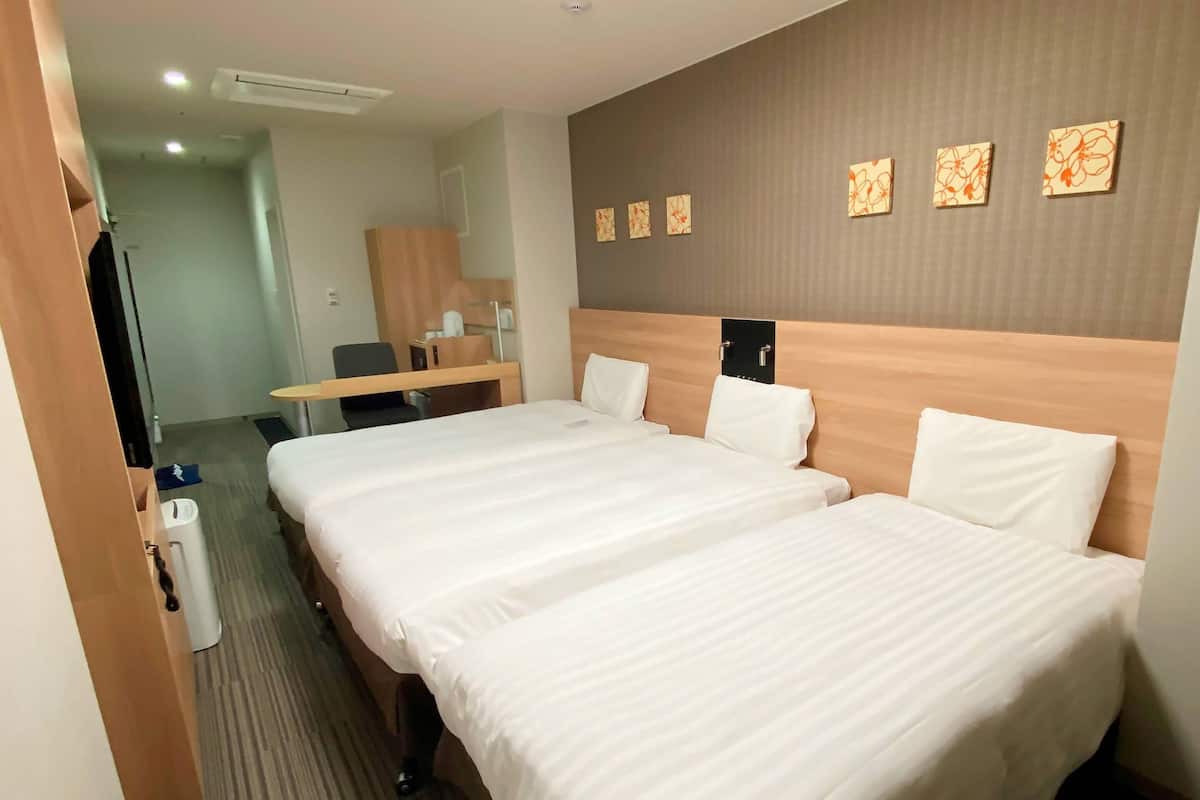 Een hotelkamer met twee bedden, een bureau en een stoel.