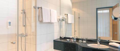 Une salle de bain moderne avec une douche à parois de verre, un plan de toilette noir, un lavabo et un miroir.