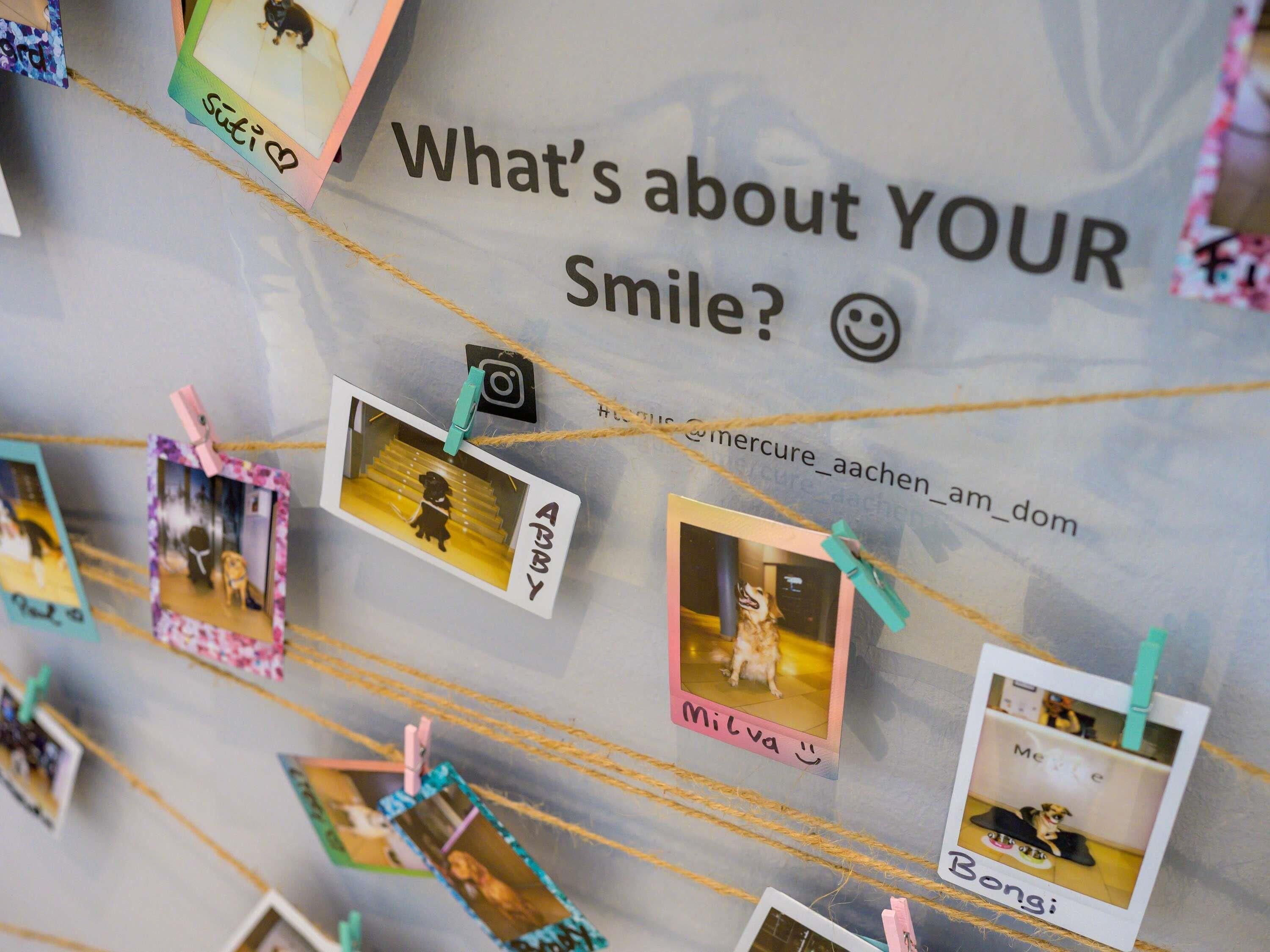 A wall with a sign reading "What's about YOUR Smile?" and several polaroid photos pinned to it.