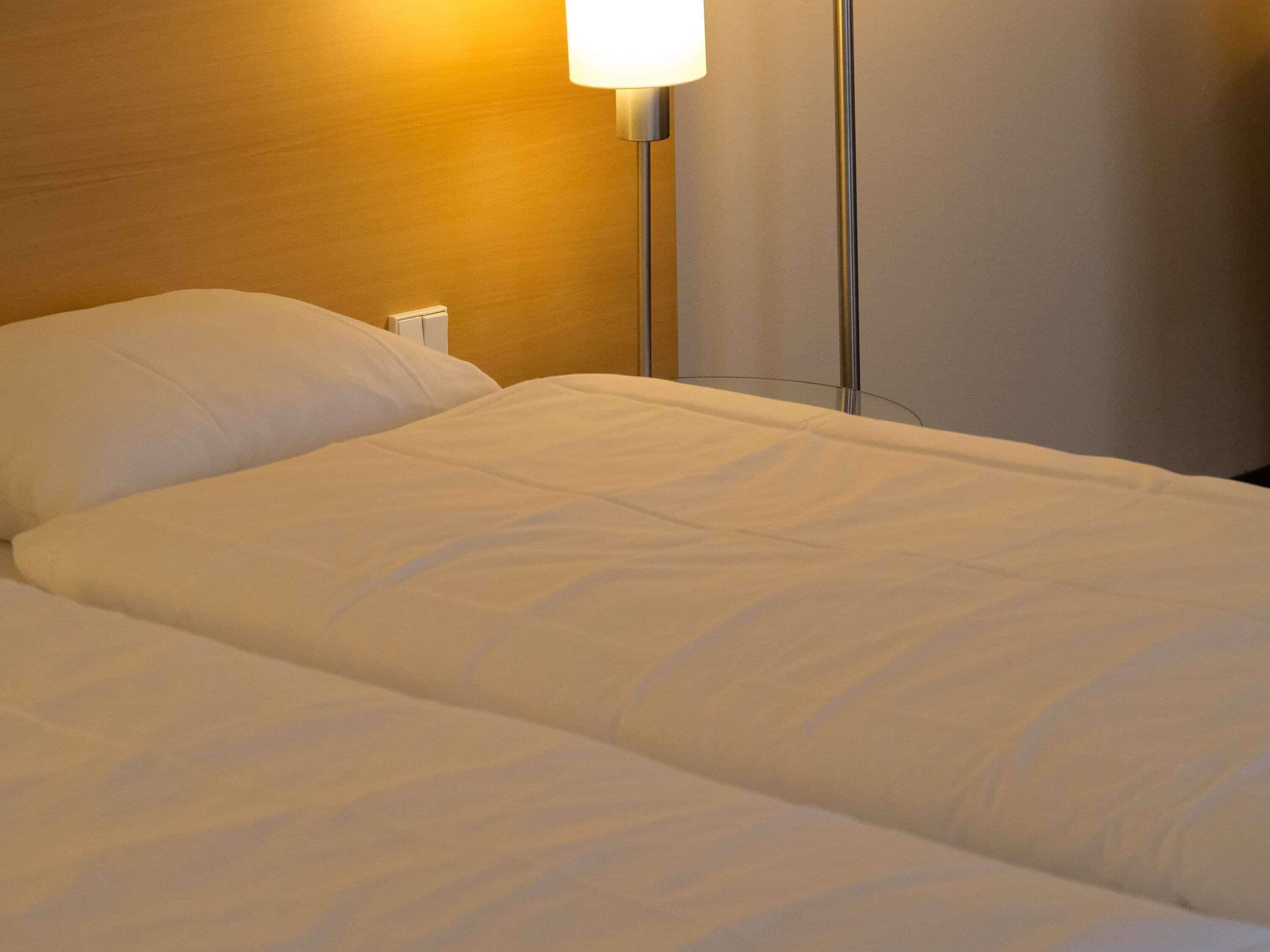 Een net opgemaakt bed met witte lakens in een hotelkamer.