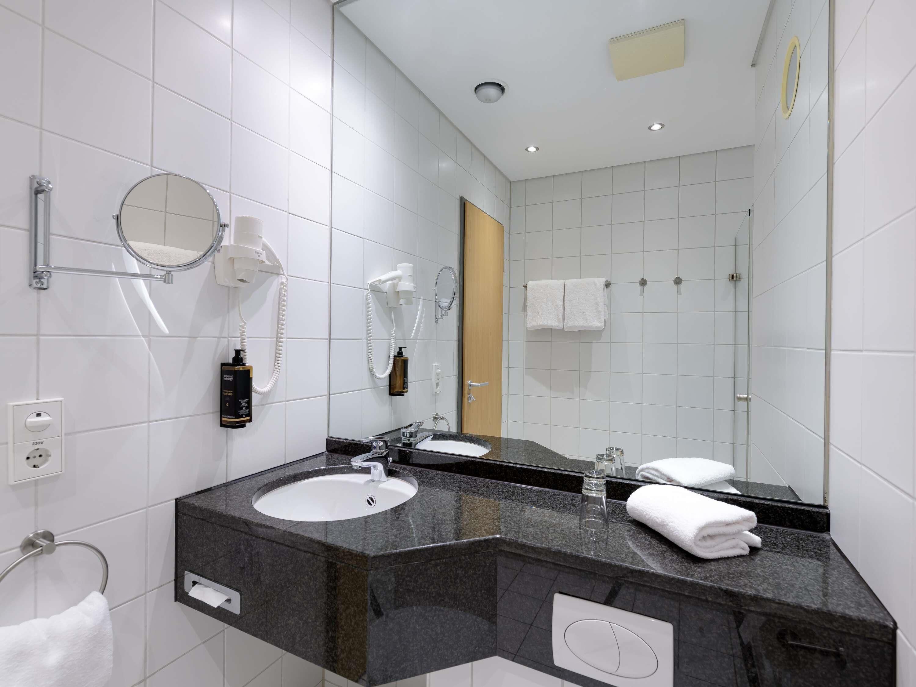Casa de banho moderna com lavatório, espelho, porta-toalhas e secador de cabelo.