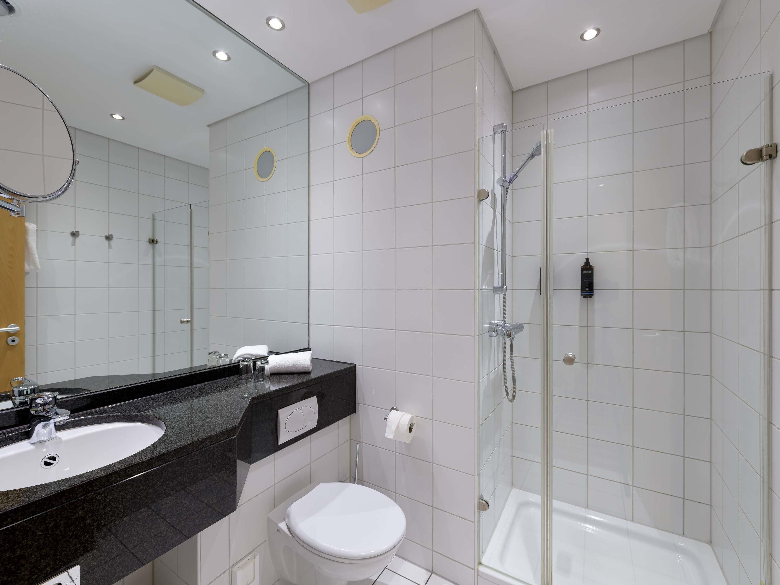 A modern bathroom with a white sink, toilet, and glass-enclosed shower.