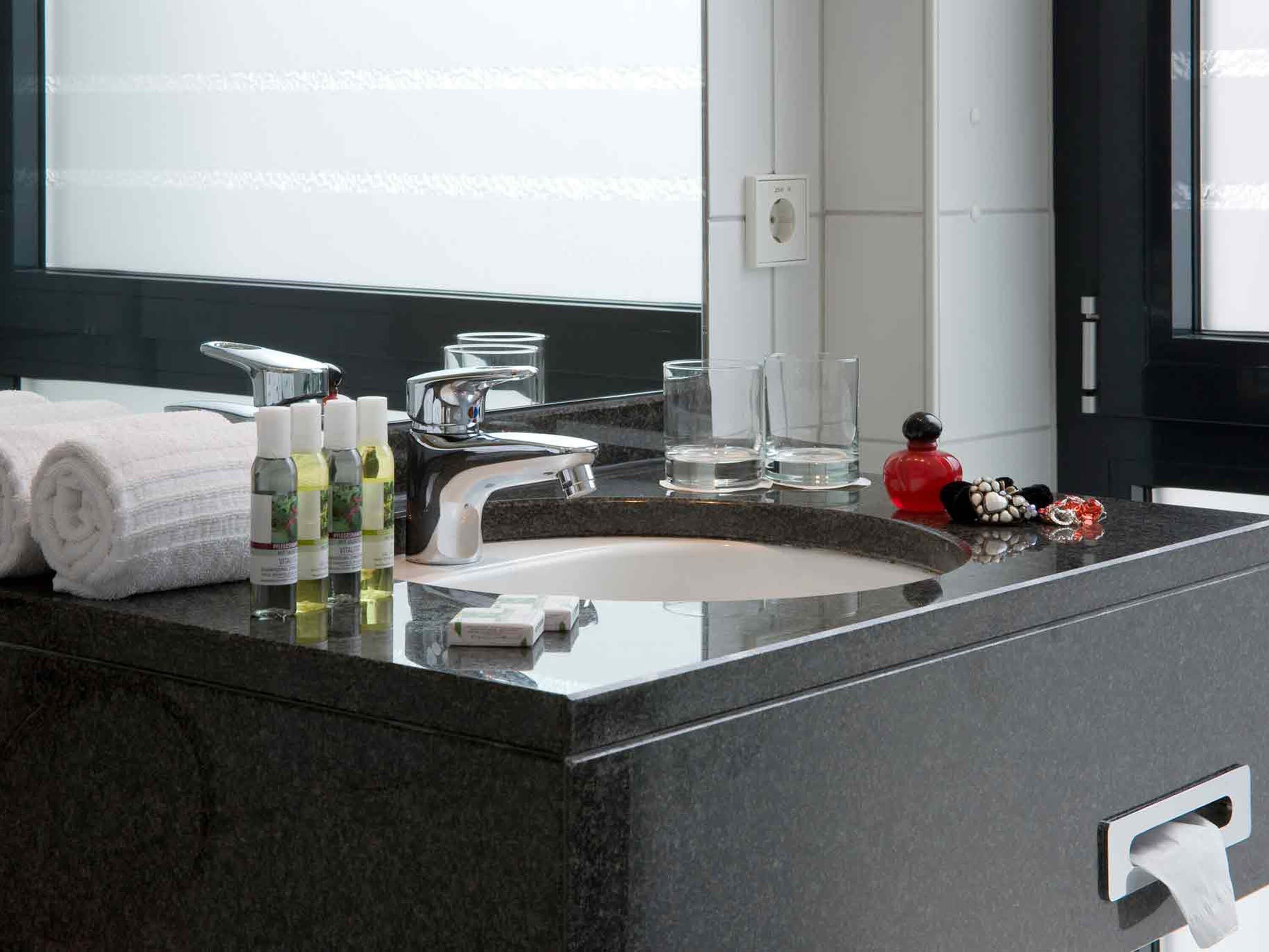 Un bagno moderno con un lavandino capiente, uno specchio e articoli da toilette.