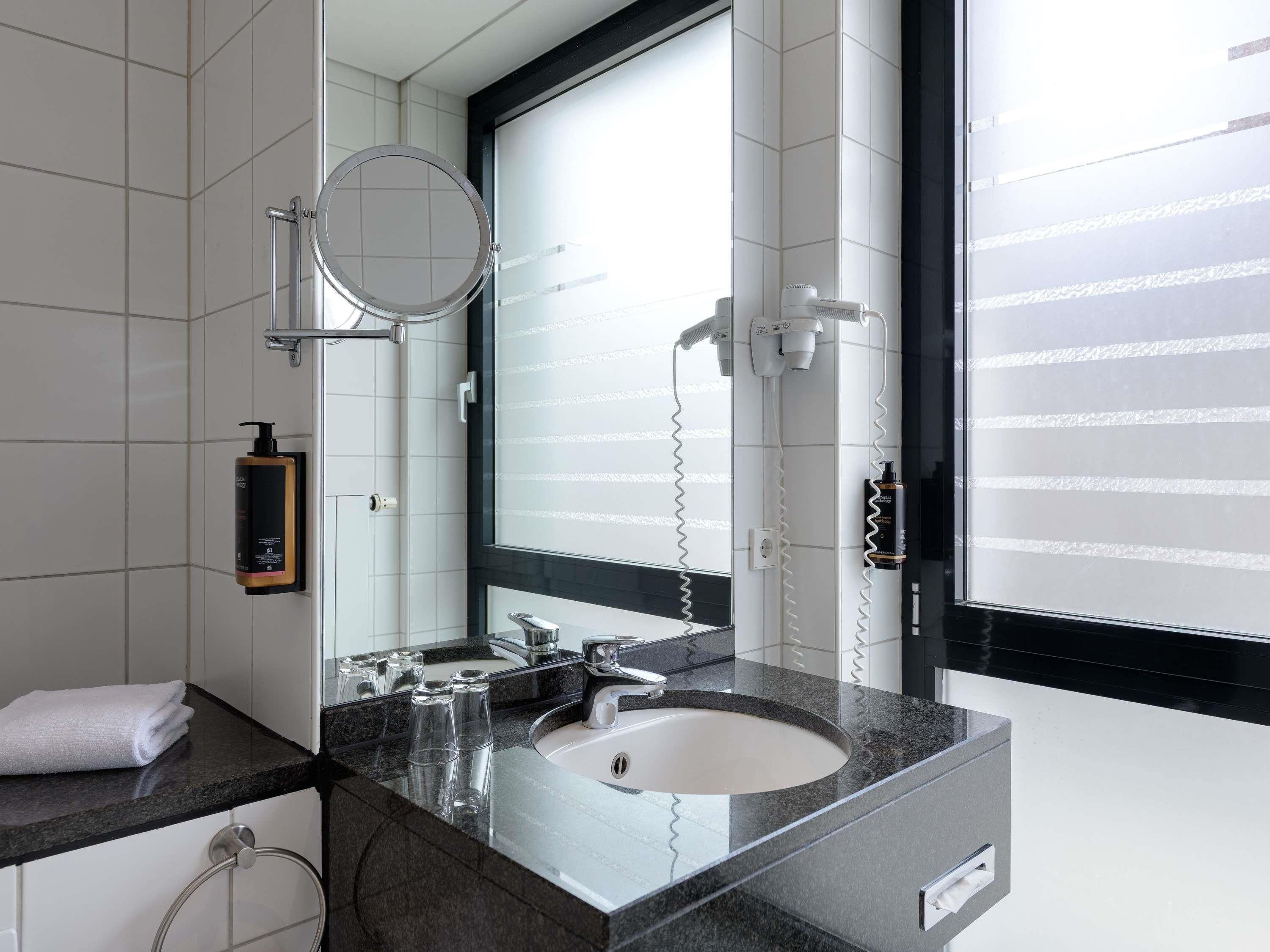 Un baño moderno con un espejo grande, un lavabo y un perchero para toallas.
