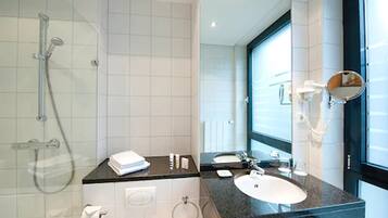 Une salle de bain moderne avec une douche à parois de verre, un plan de toilette noir, un lavabo blanc et un grand miroir.