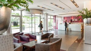 A lobby with seating areas, a reception desk, and large windows.