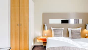 A hotel room with a bed, a wardrobe, bedside tables, and a mirror.