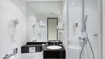 Un baño moderno con ducha, lavamanos, inodoro y espejo.