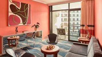 Una sala de estar moderna con un sofá, sillas, una mesa de centro, una mesa de comedor y un ventanal con cortinas.