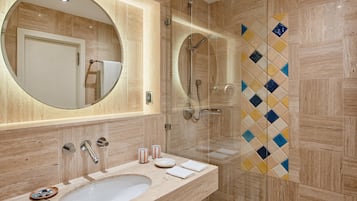 Un baño moderno con un espejo ovalado grande, un lavamanos y una zona de ducha.