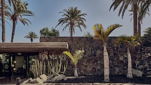 A spa wellness center with a stone wall, palm trees, and cacti. - Seaside Palm Beach (San Bartolomé de Tirajana)