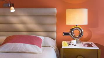 A neatly made bed with a pillow, a bedside lamp, and a magazine on a wooden nightstand.