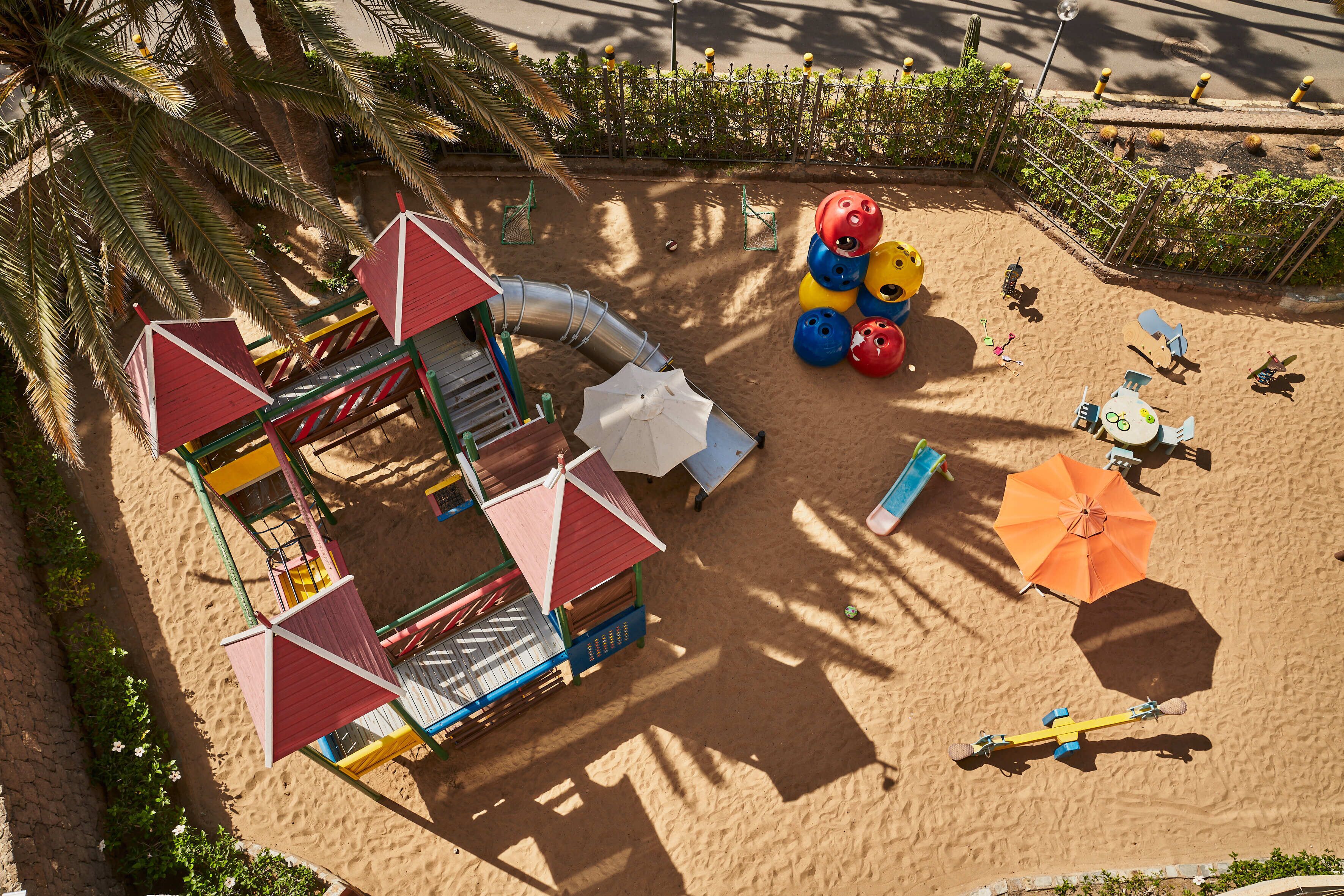 Un parque infantil con toboganes, columpios y un arenero.