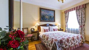 Una habitación de hotel con una cama grande, dos lámparas de noche, un cuadro en la pared y una ventana con cortinas.