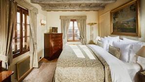 A hotel room with a large bed, a dresser, a window with curtains, a painting on the wall, and a radiator. - Golden Well Hotel (Prague)