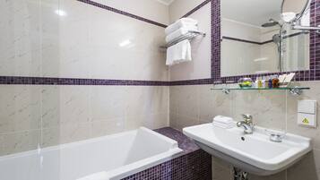 Ein modernes Badezimmer mit einer weißen Badewanne, einem Waschbecken mit Glasbecken und einem Spiegel über dem Waschbecken.