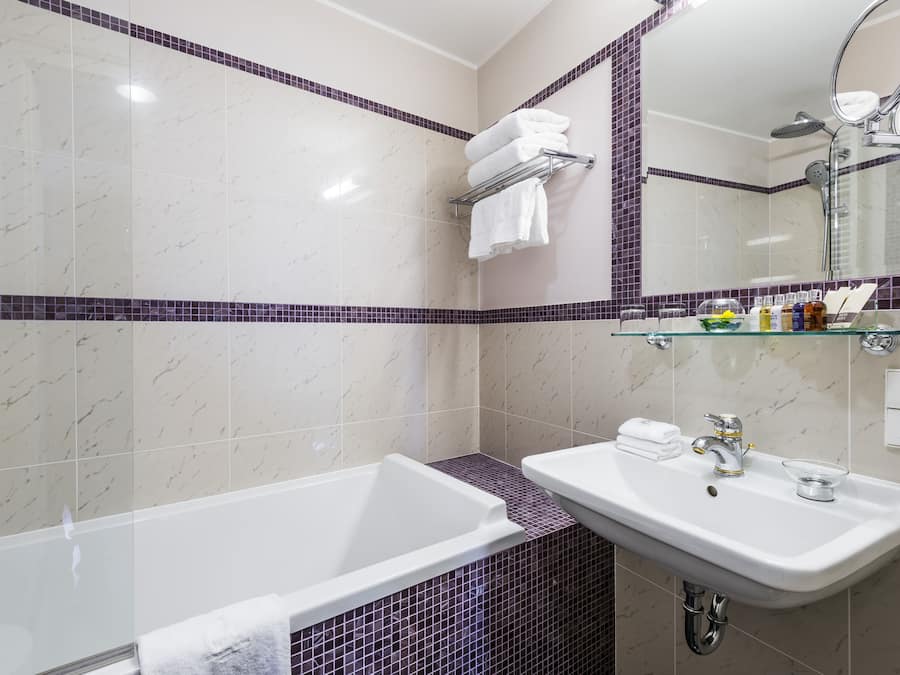 Ein modernes Badezimmer mit einer weißen Badewanne, einem Waschbecken mit Glasbecken und einem Spiegel über dem Waschbecken.