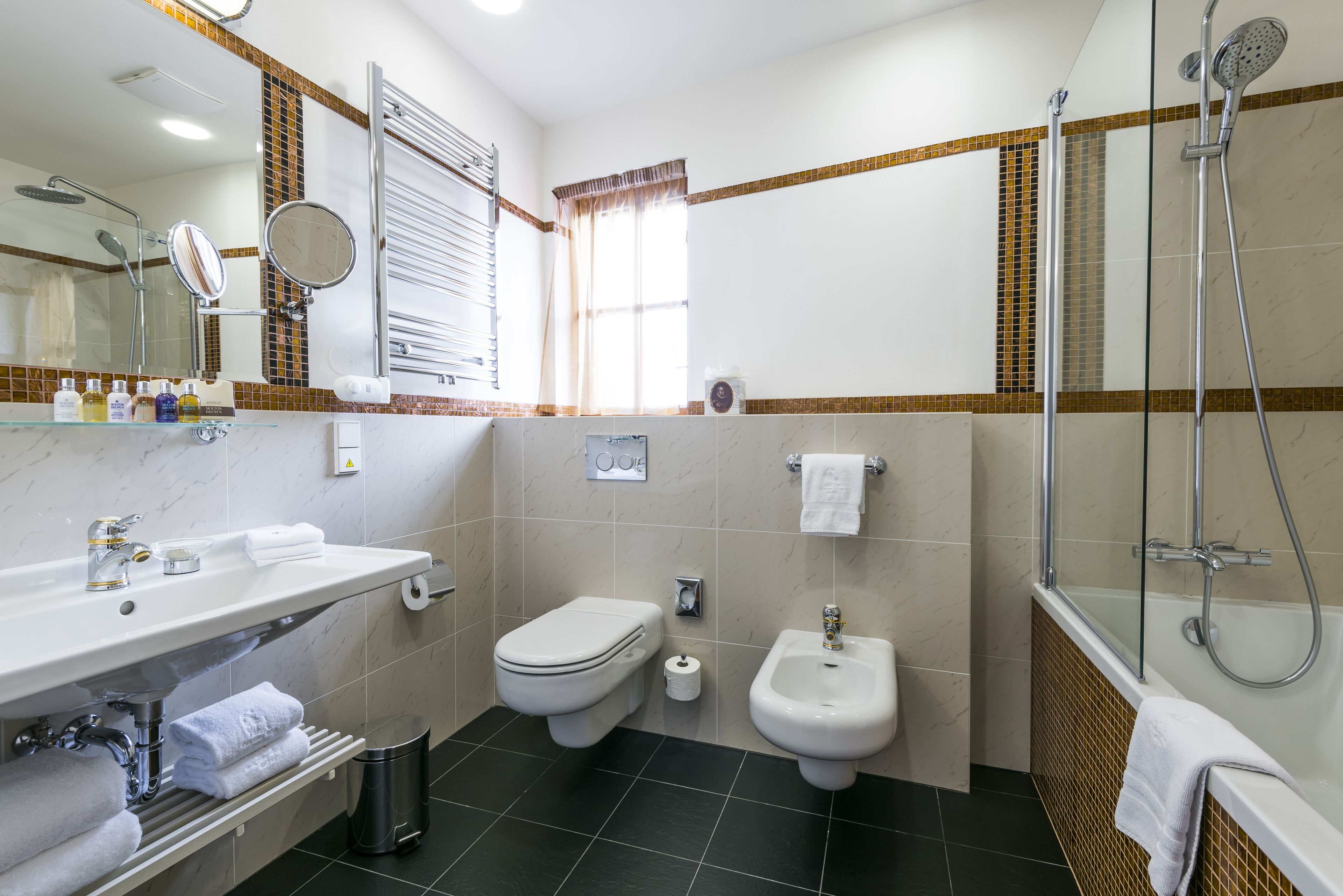 A modern bathroom with a white sink, a toilet, a bidet, and a shower.