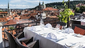 A dining table set for a meal with a view of a cityscape. - Golden Well Hotel (Prague)