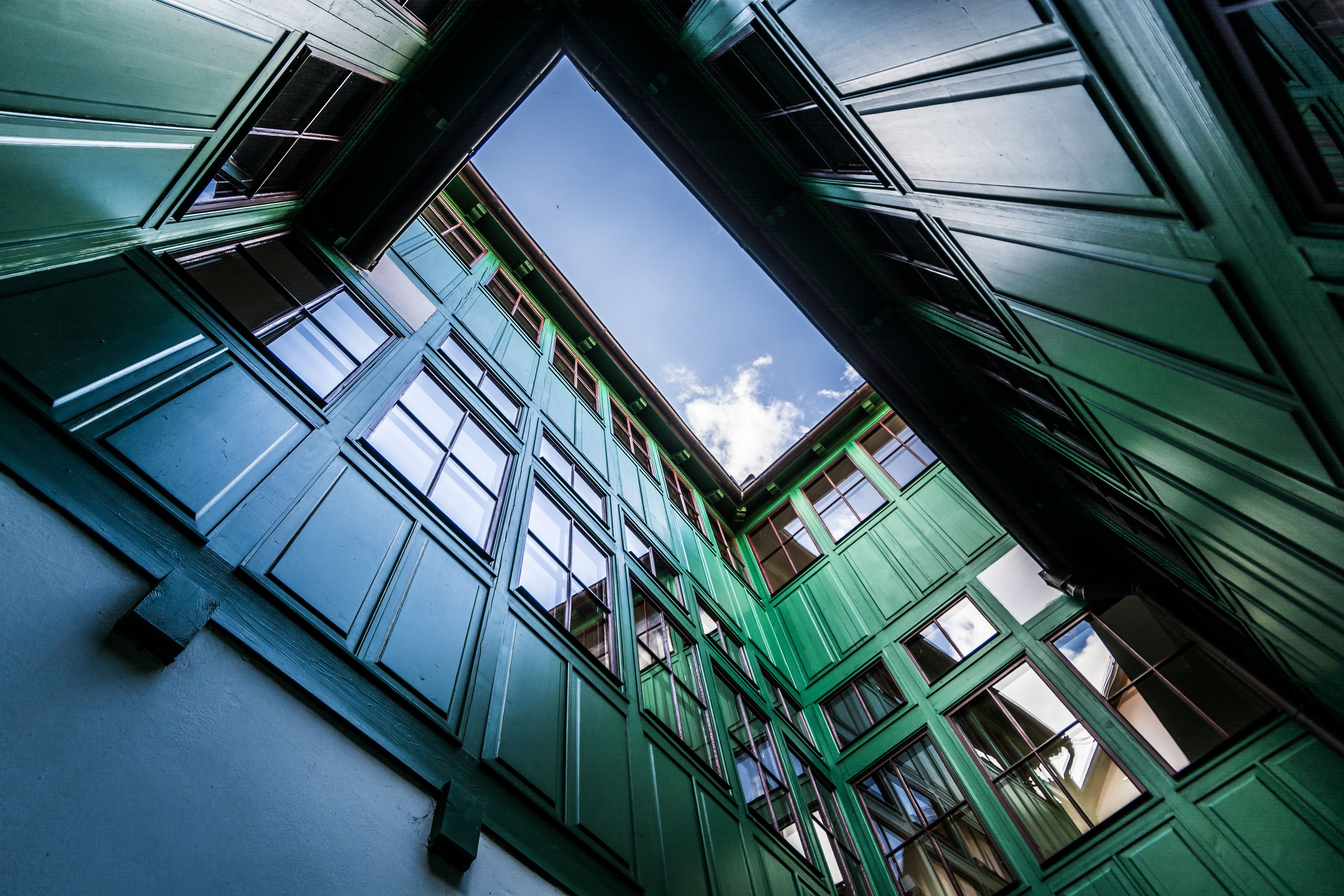 Un edificio de varios pisos con fachada verde y numerosas ventanas.