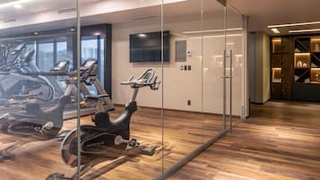 Un gimnasio moderno con bicicletas estáticas, un espejo grande y suelo de madera.