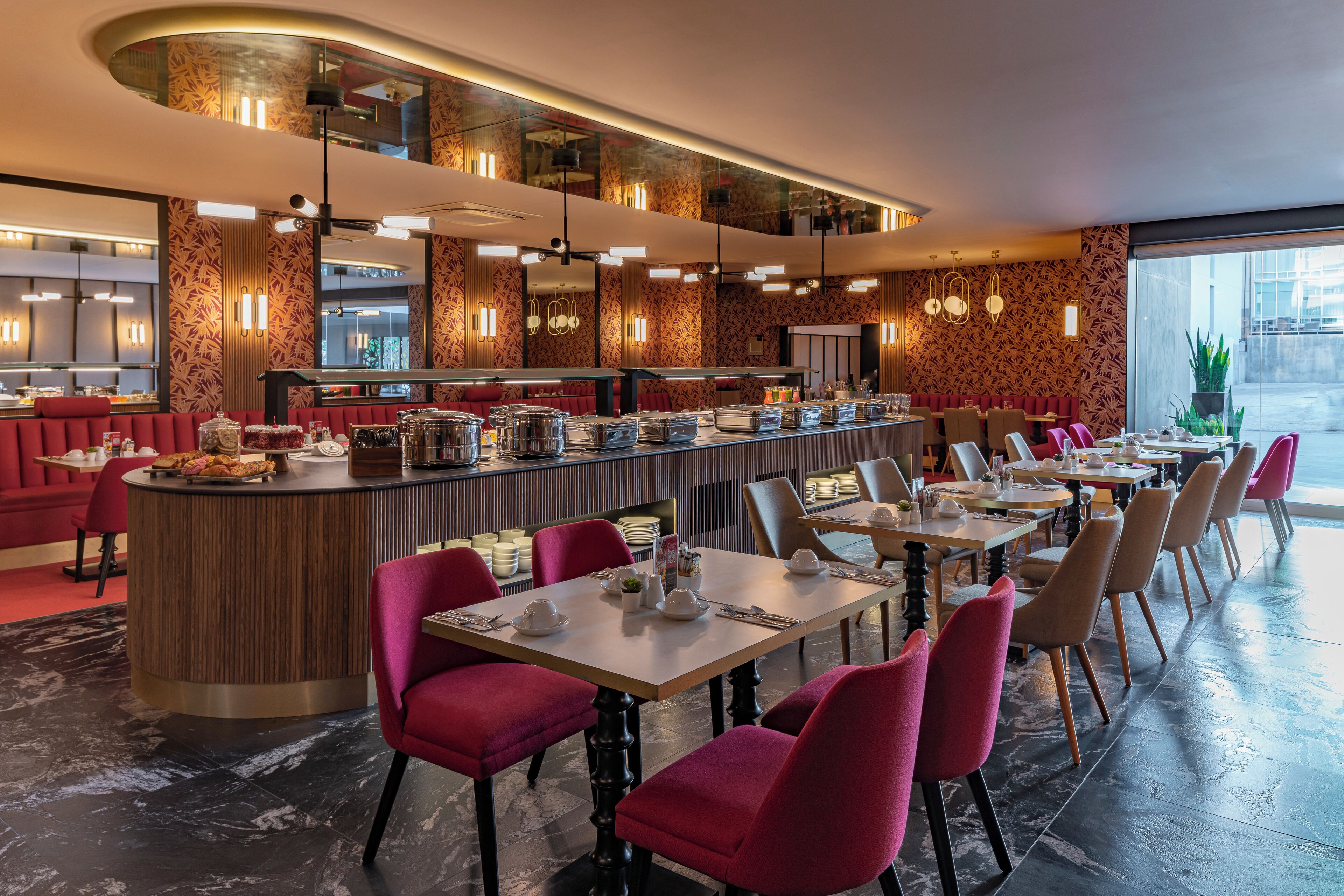 En moderne restaurant med en lang disk, røde siddepladser og udsigt til gaden.