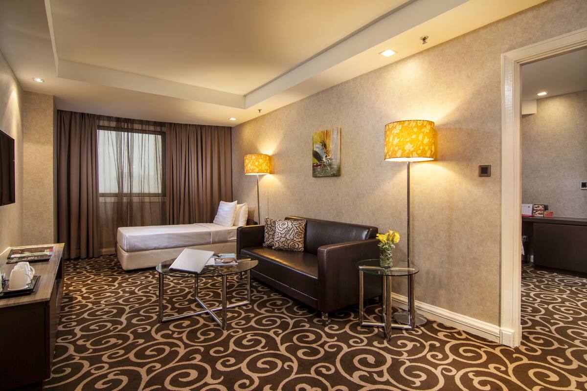 Ein Hotelzimmer mit Bett, Sofa, Schreibtisch mit Lampe und Teppichboden.